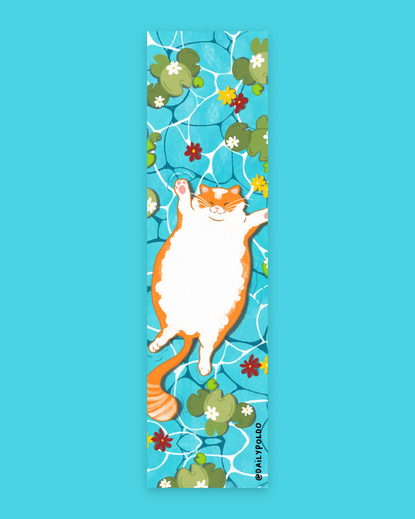 Gatto arancione e bianco a pancia all'aria che galleggia in acqua turchese tra ninfee e fiori bianchi, gialli e rossi